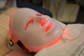 Mujer usando la máscara LED de terapia facial Tibia con luz roja durante una sesión en casa
